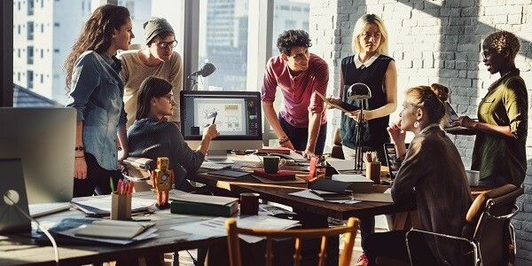 Team di giovani professionisti che stanno collaborando in ufficio, rappresentando il lavoro di squadra e l’impegno nel sociale dell’azienda.