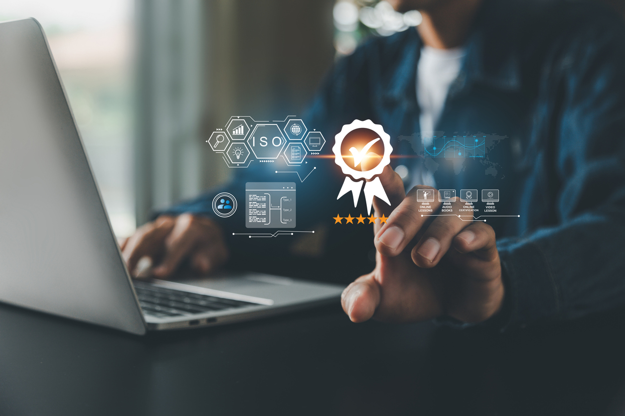 Professionista al computer che seleziona simboli digitali di standard di qualità, certificazioni ISO e soluzioni tecnologiche per aziende.